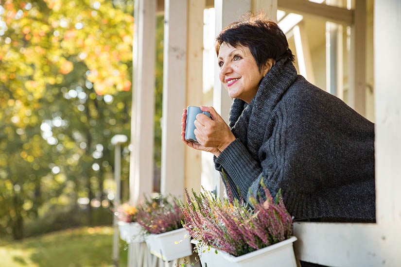 Mature woman looking out from porch thinking about a bright future