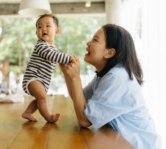 Doting mother plays with her growing baby, confident that her family's financial wellness is intact