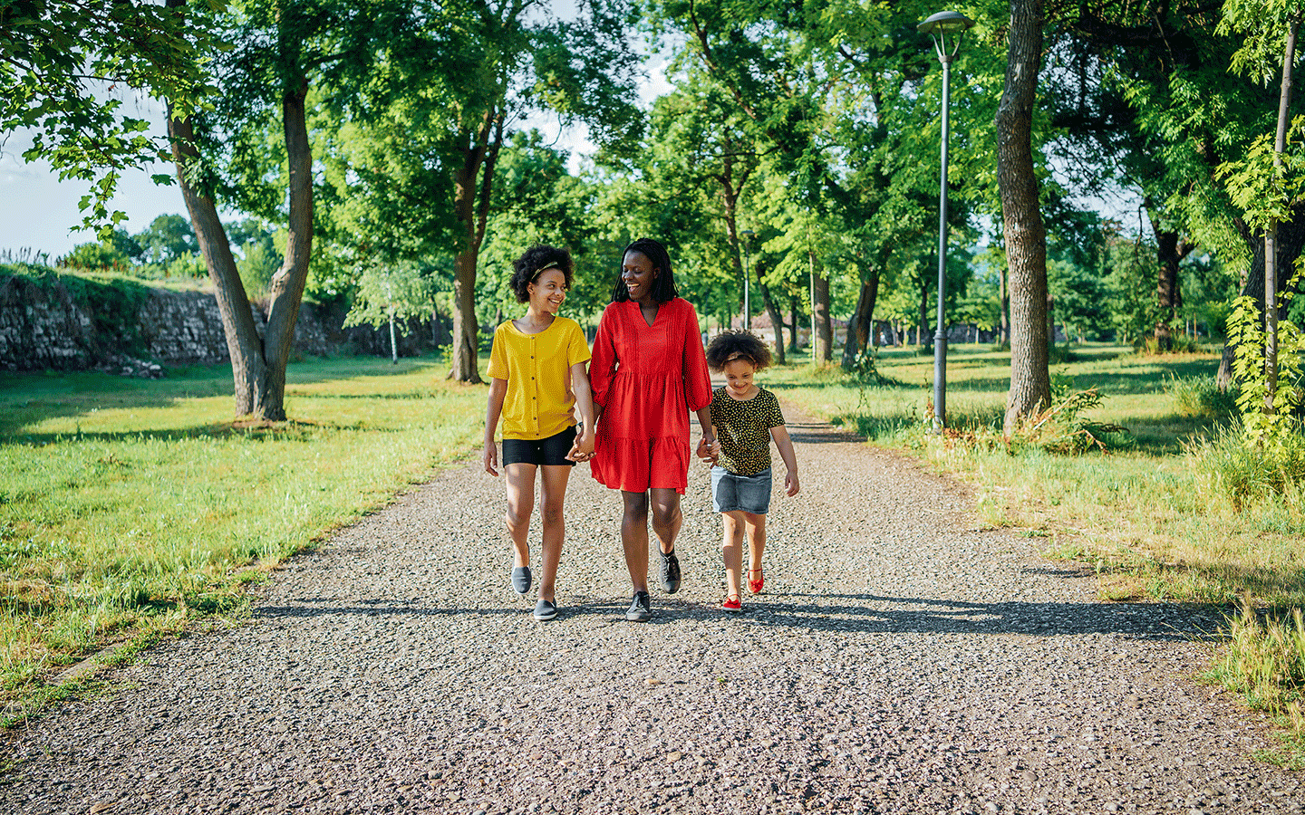mom and two children walking down a path in the park