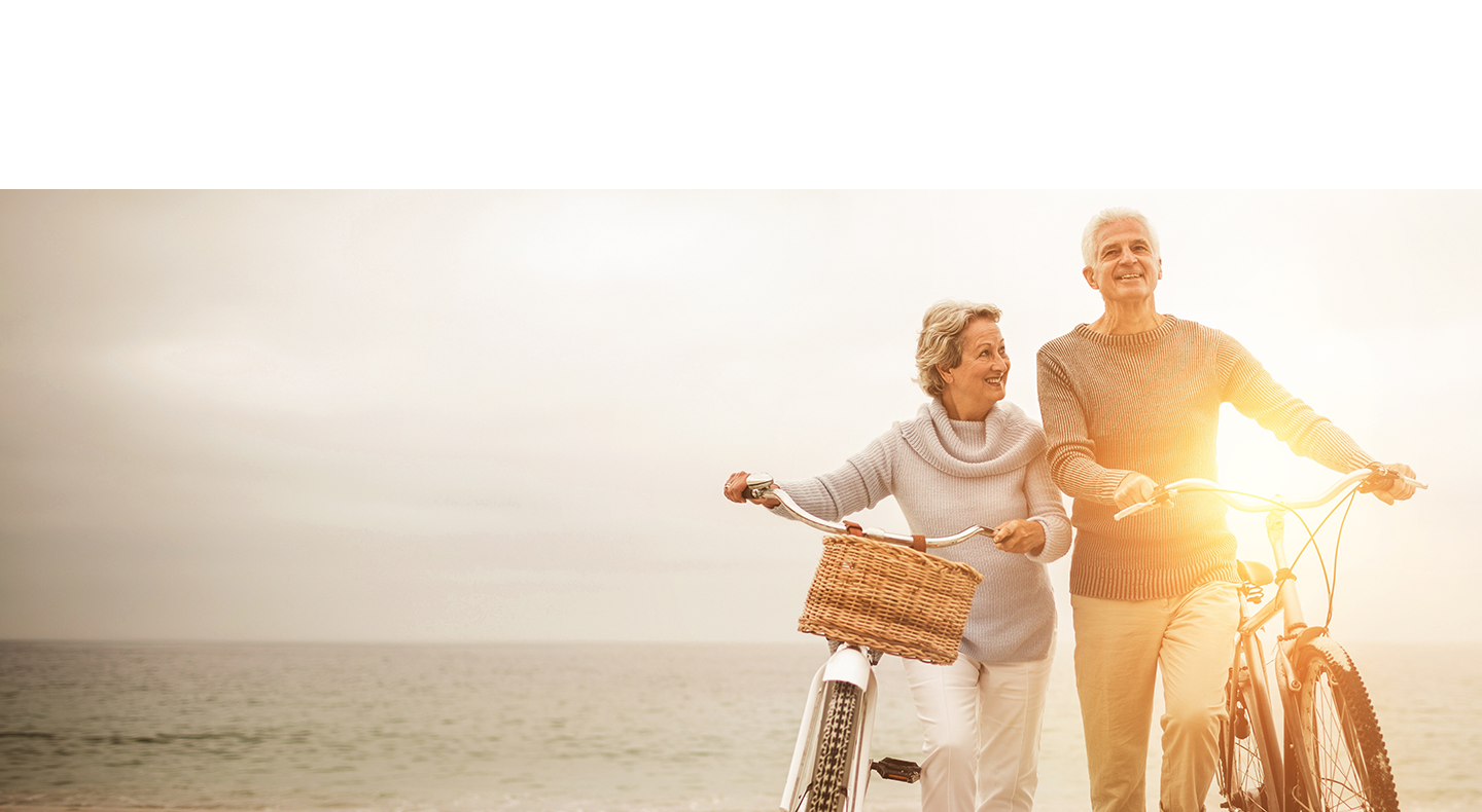 Retired couple bike riding on beach