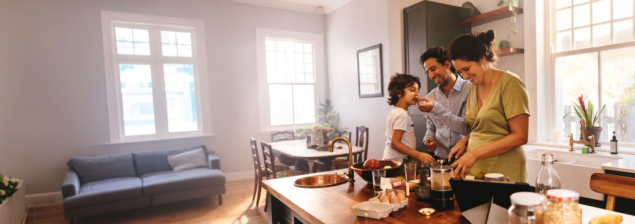Playful dad feeding his son a slice of bread in the kitchen