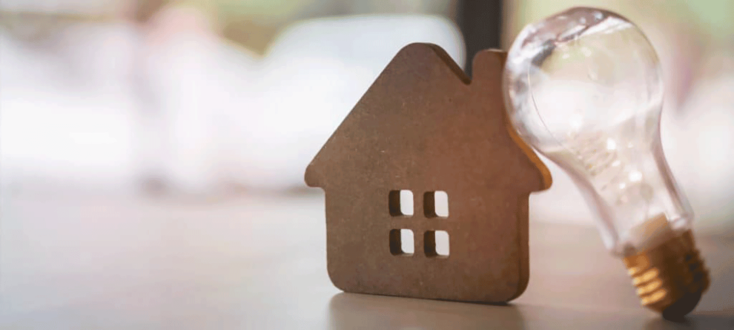 lightbulb leaning against wooden house