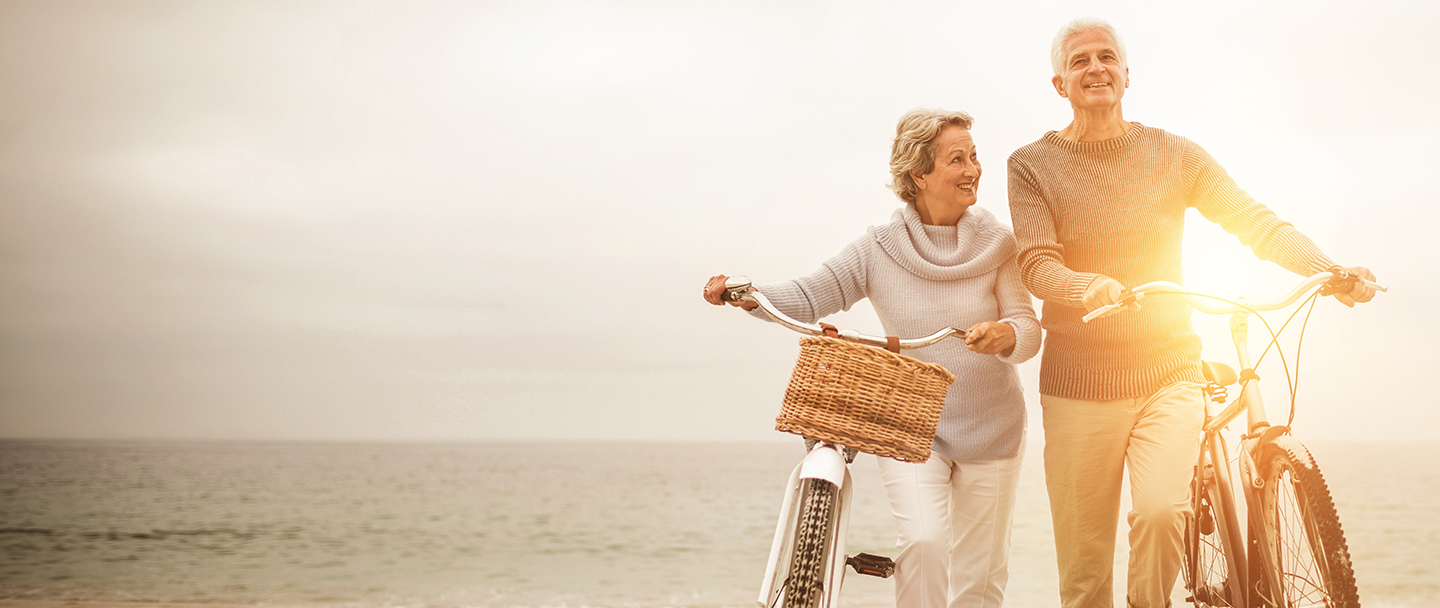 Retired couple bike riding on beach