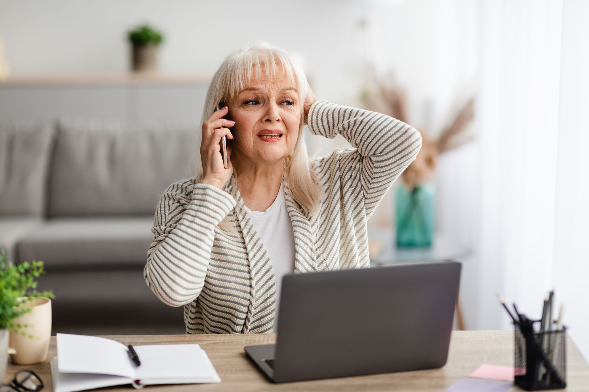 Image of woman on mobile phone and laptop concerned about fraud