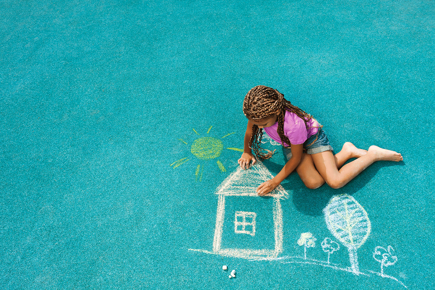 young girl drawing a house with chalk