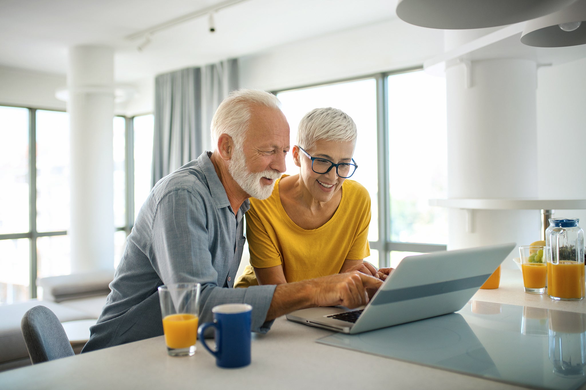 Closeup top view of a mid 60's couple sitting at a kitchen counter and doing some online shopping.