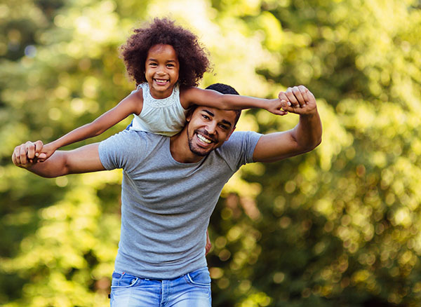 Portrait of young father carrying his daughter on his back