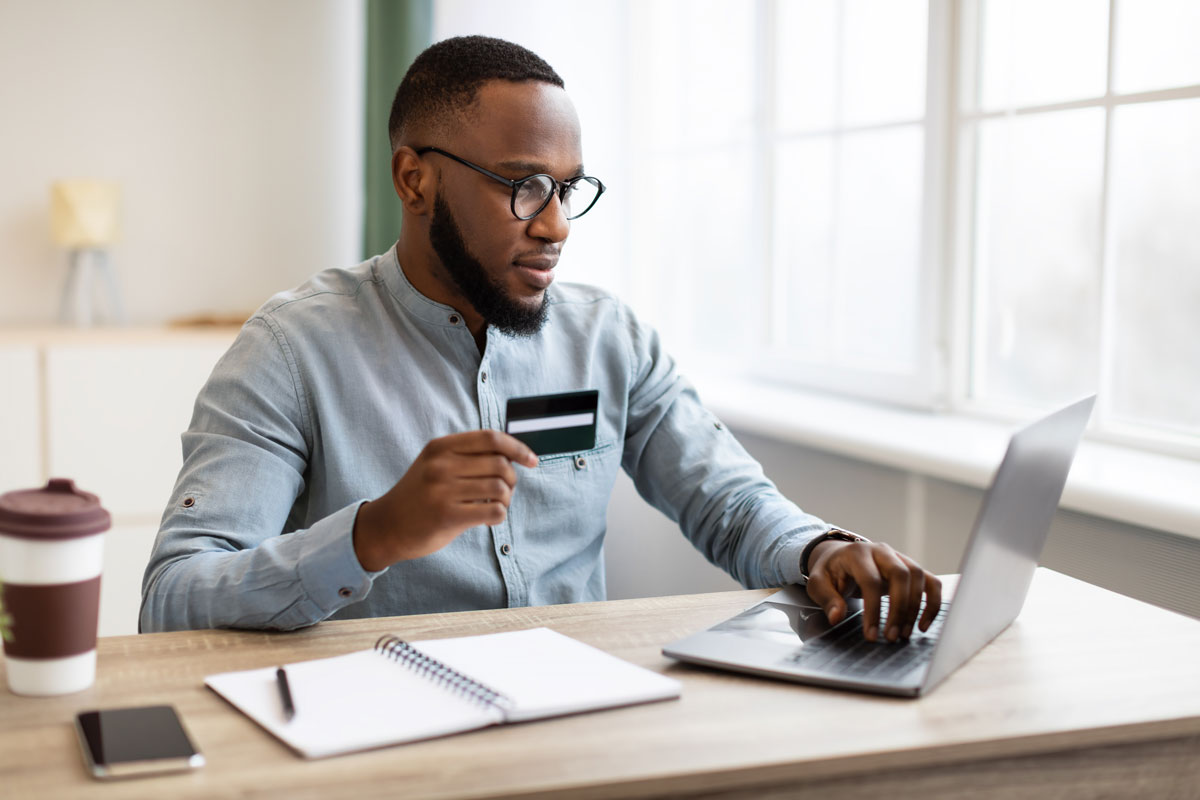African American Businessman Using Credit Card And Laptop In Office